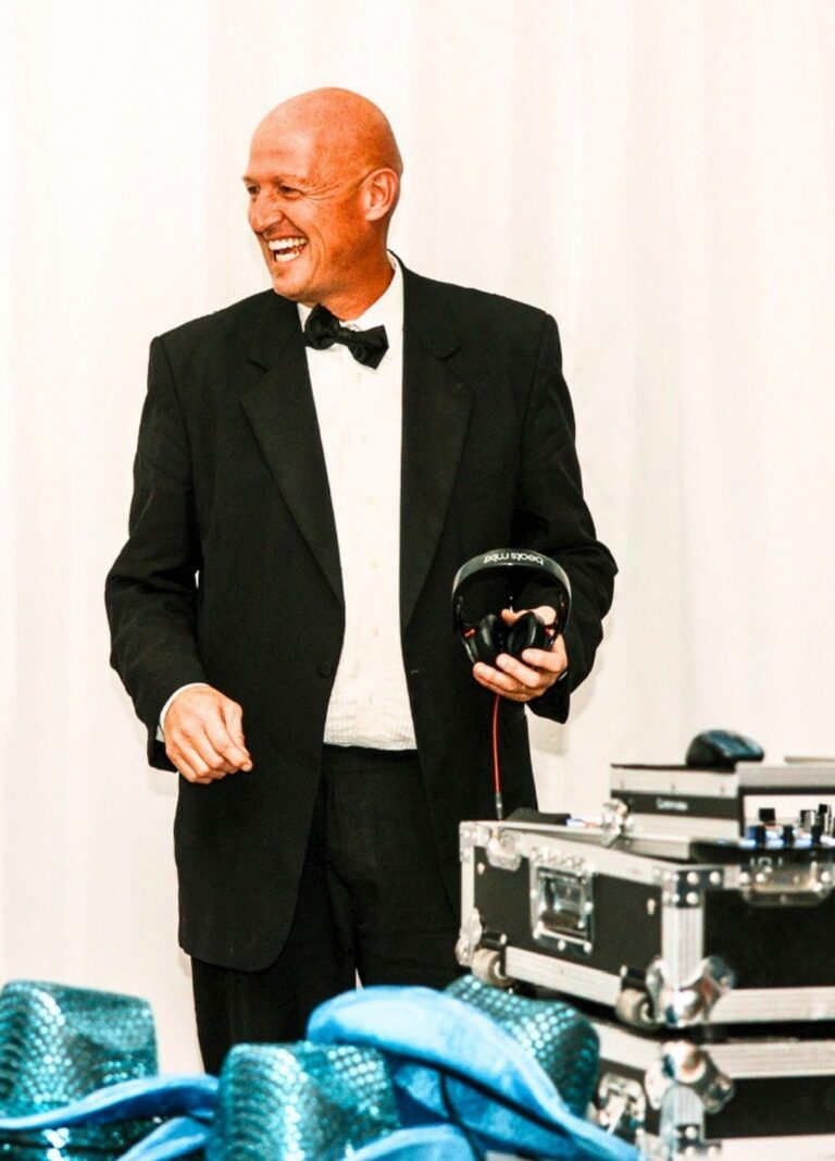 DJ in formal tuxedo holding headphones at A & B Productions event.