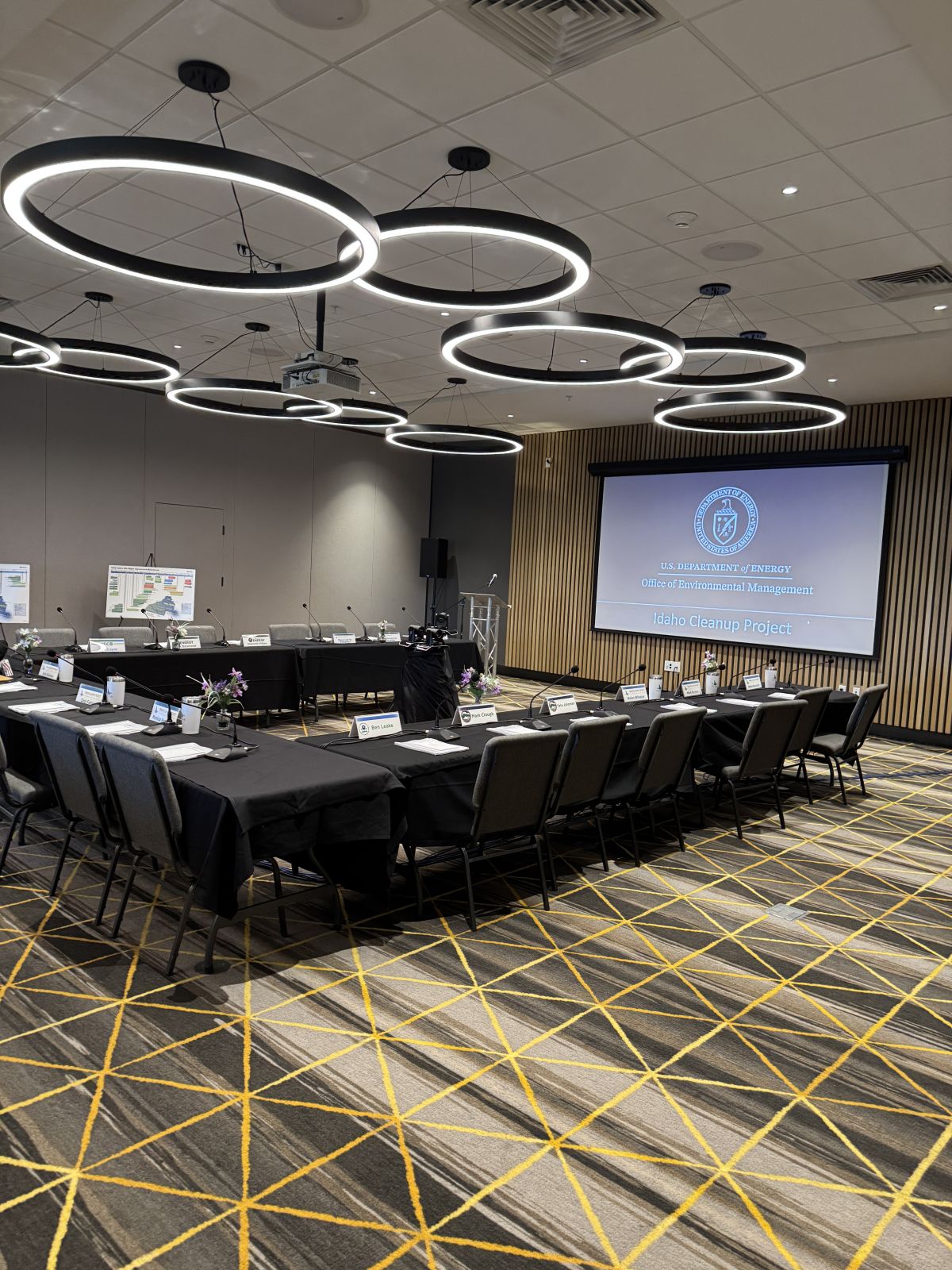 Meeting room set with tables, chairs and a projection screen, ready for a live streamed public meeting